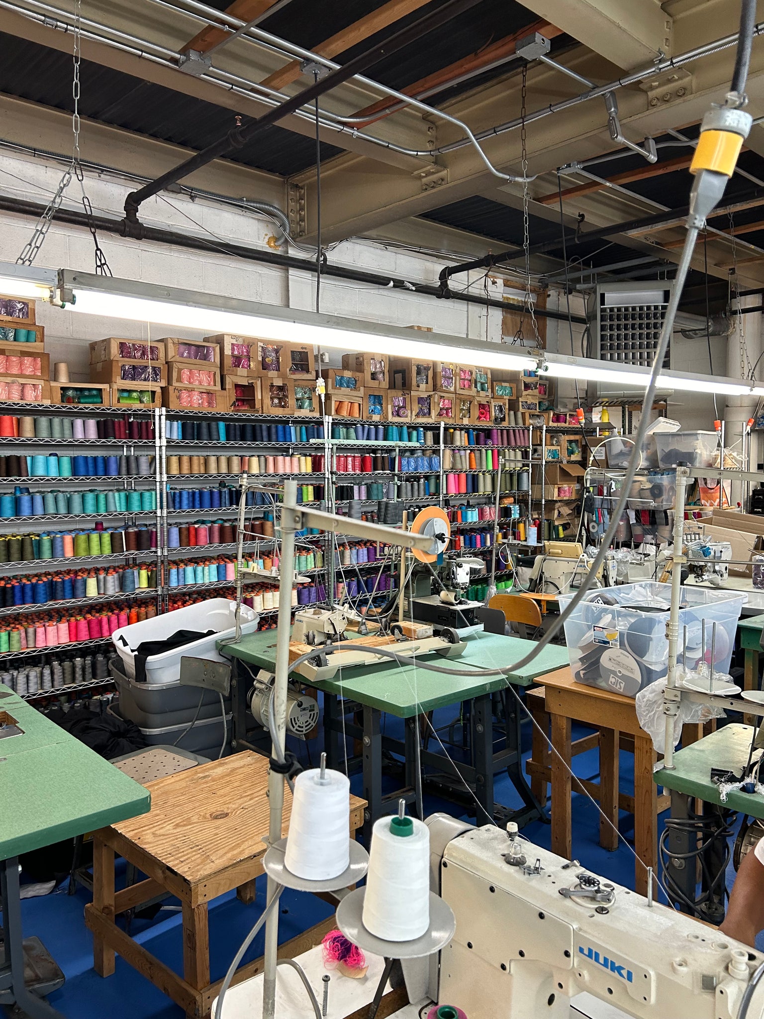 Textile factory with spools of thread and machinery like sewing machines and steamers 