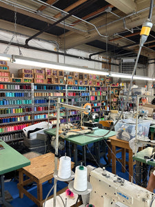 Textile factory with spools of thread and machinery like sewing machines and steamers 