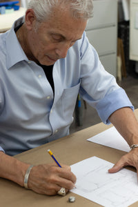 Anthony Lilore sketching clothing designs on paper at a desk in an office setting